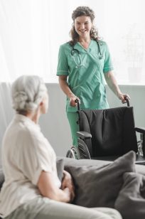 attractive-young-female-nurse-bringing-wheelchair-senior-patient